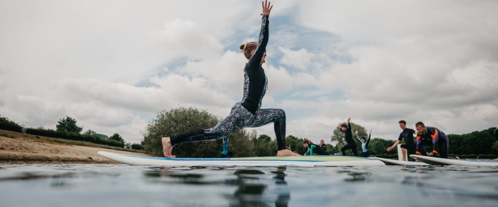 woman in black tank top and black leggings doing yoga on blue yoga mat on water